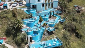 A large, multi-story building with a central courtyard, surrounded by lush greenery and hills. - Hotel y Termales Castillo del Lago (El Peñol)