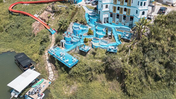 A resort with a water park, a dock with boats, and a large building with blue domes. - Hotel y Termales Castillo del Lago (El Peñol)