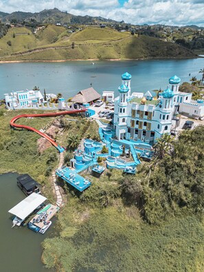 A resort with a water park, a dock with boats, and a large building with blue domes. - Hotel y Termales Castillo del Lago (El Peñol)