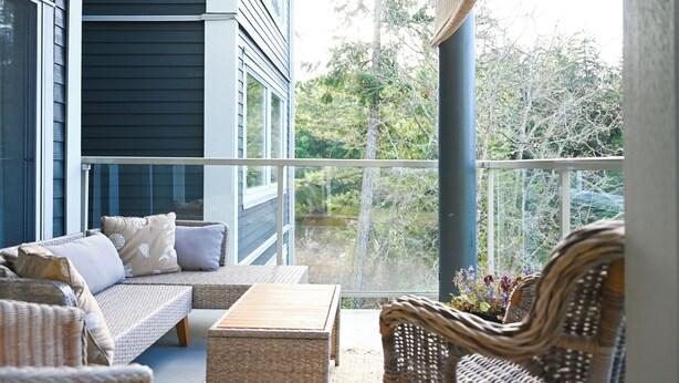 A balcony with wicker furniture, including a sofa and chairs, and a small table.