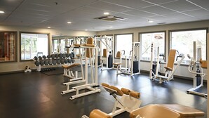 A gym with various exercise machines, dumbbells, and benches.