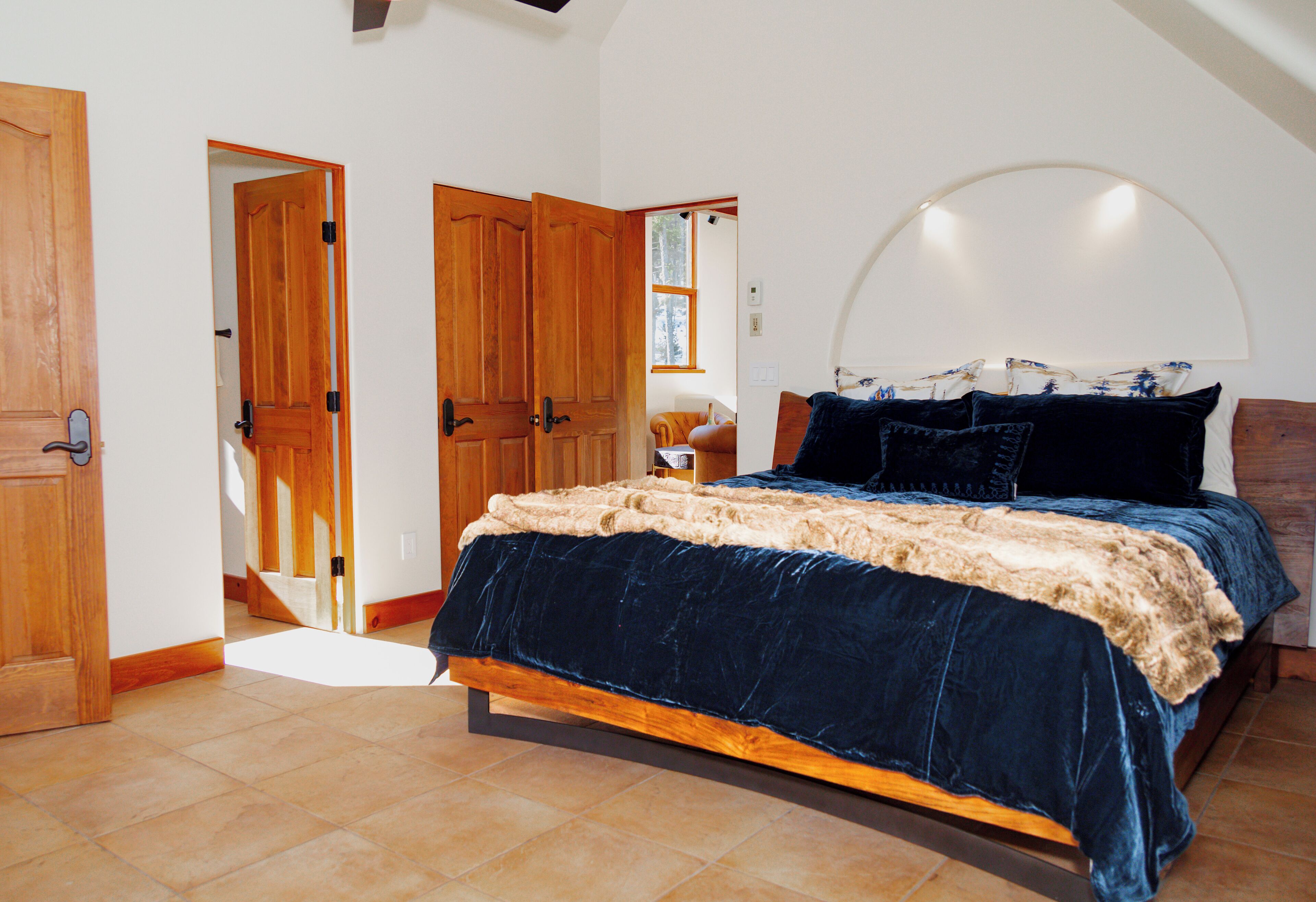 A bedroom with a bed, wooden doors, and a large window.
