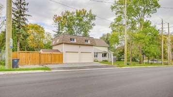 A two-story house with a garage, a wooden fence, and a driveway leading to a street.
