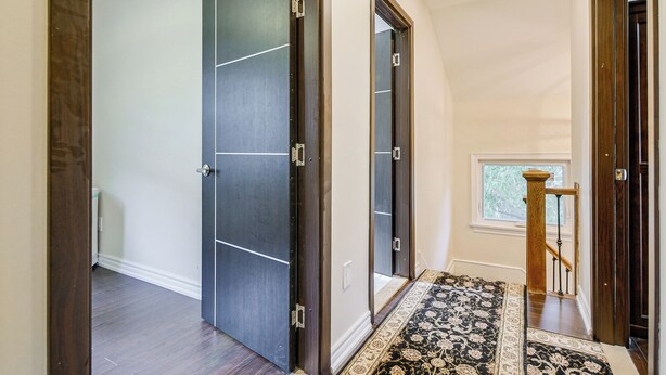 A hallway with a dark wooden door, a white wall, and a patterned rug. - Room in Guest Room - Queen Room 2 Brampton Toronto Canada (Brampton)