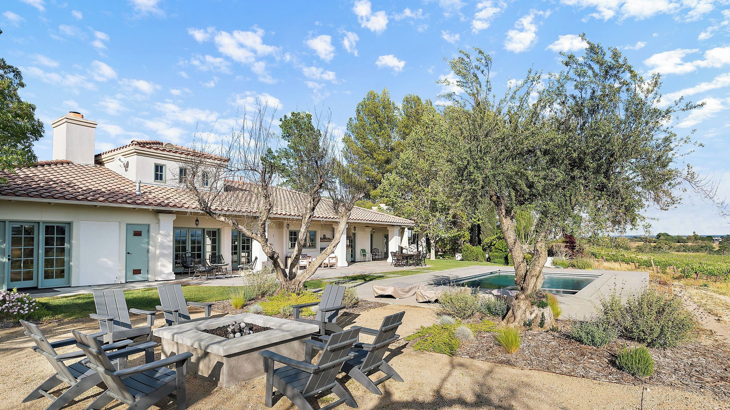 Una casa con patio, mobiliario exterior y piscina.