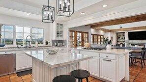 A spacious kitchen with a large island, white cabinetry, and a built-in stove. - 40-acre Wine Trail Estate Vineyard Views, Pool, Hottub Wellsona by Avantstay (Paso Robles)