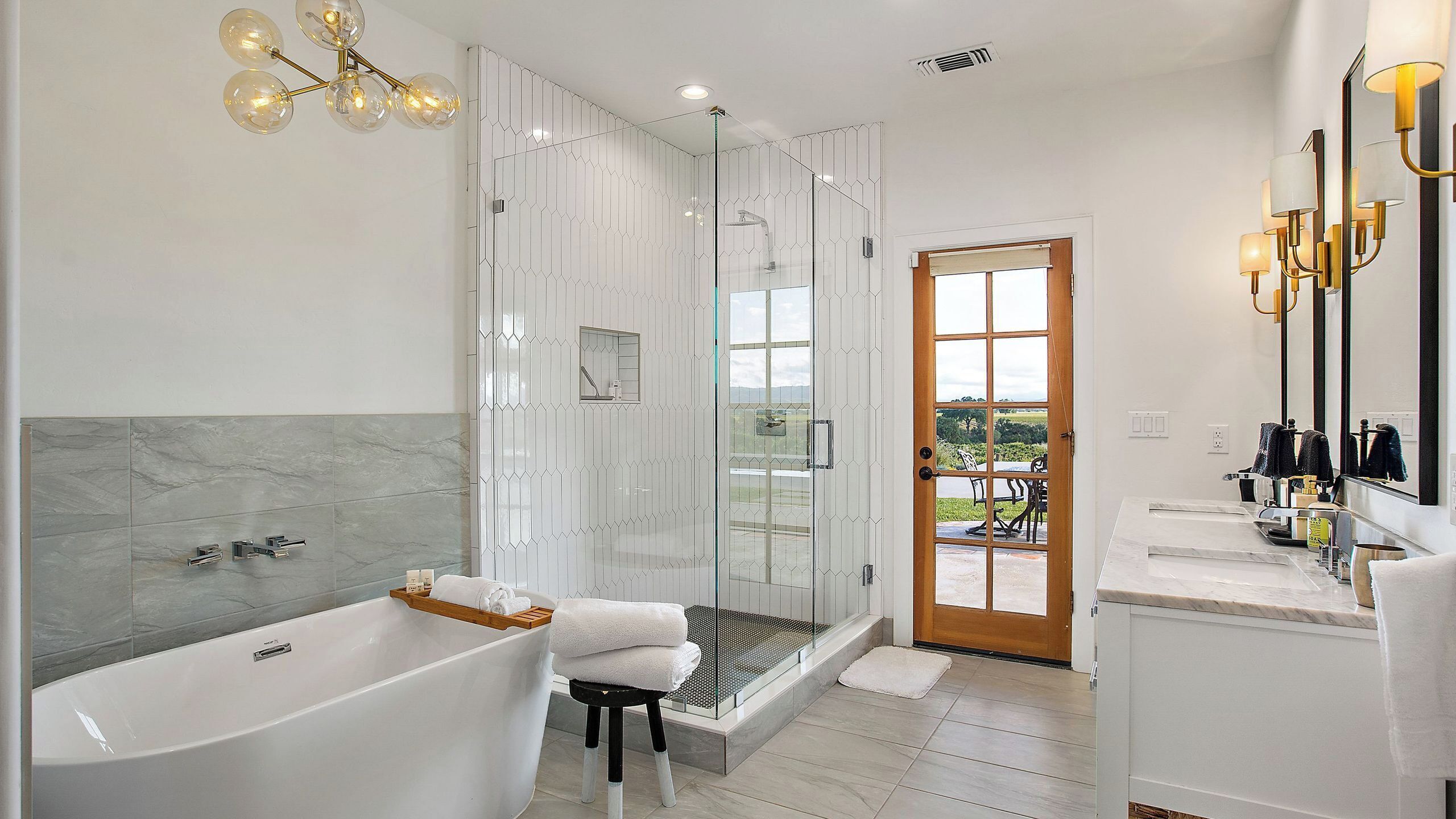 A modern bathroom with a glass-enclosed shower, a freestanding bathtub, and a vanity with a mirror.