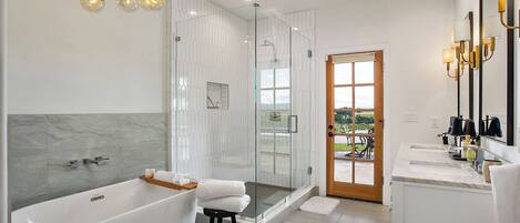 A modern bathroom with a glass-enclosed shower, a freestanding bathtub, and a vanity with a mirror.
