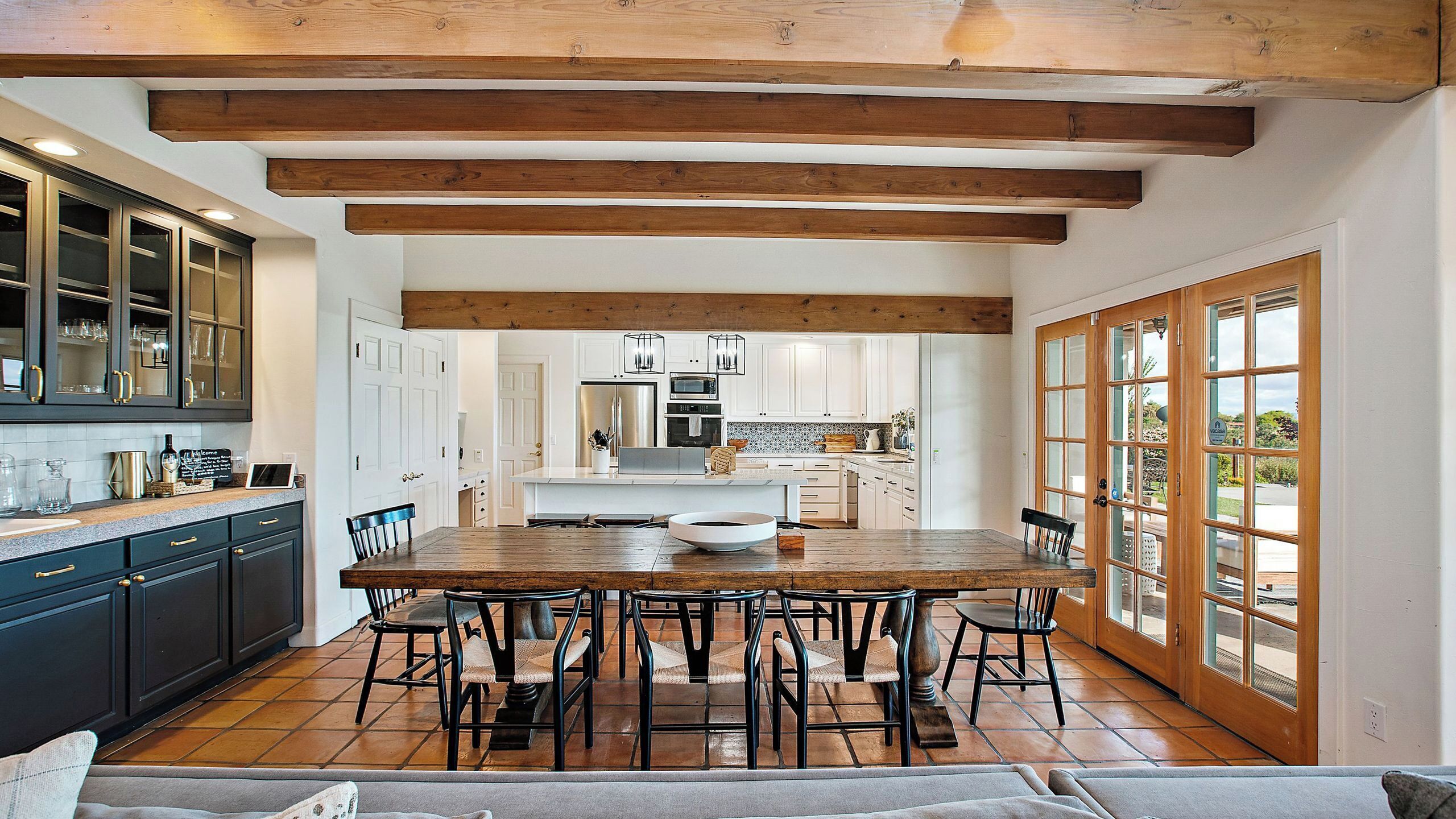 A spacious kitchen with a large island, dark cabinets, and a dining area with a wooden table and chairs.