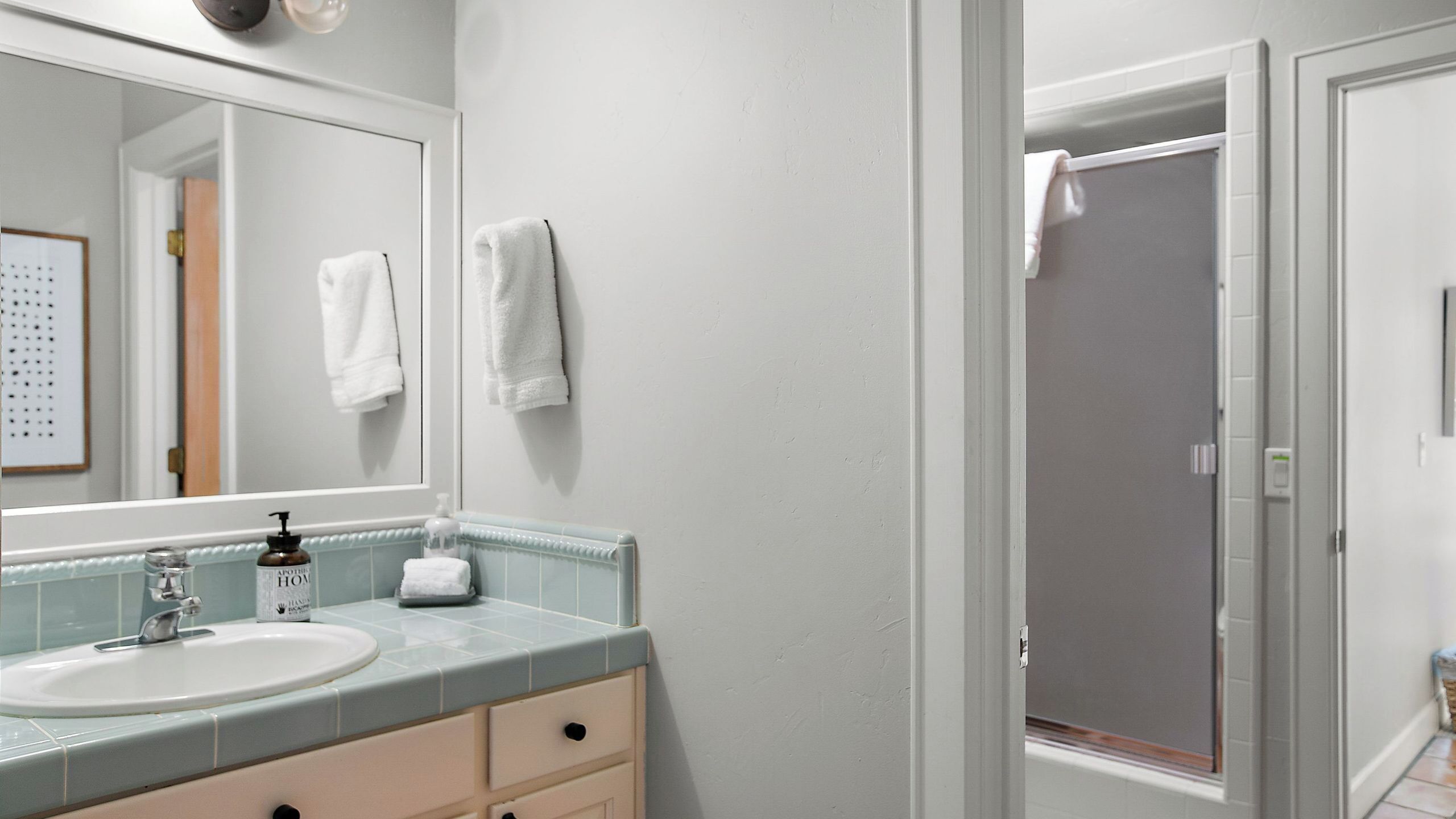 A bathroom with a sink, mirror, and towel rack.