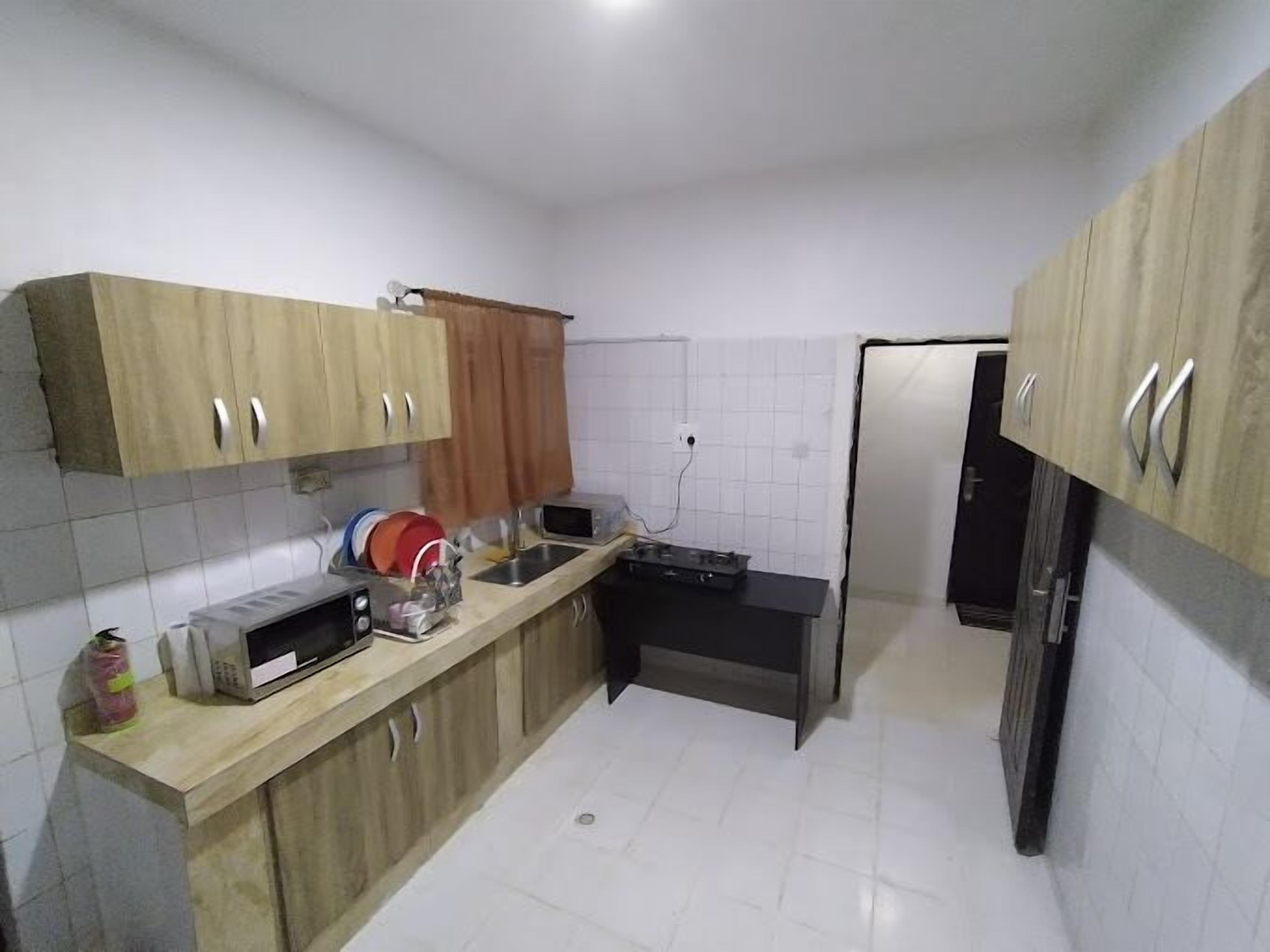 Una cucina compatta con mobili in legno, un forno a microonde, un lavello e un frigorifero.