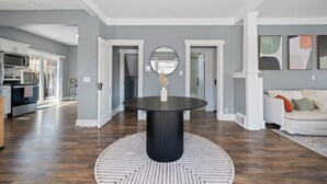 A modern living room with a round black table, grey walls, and a wooden floor.