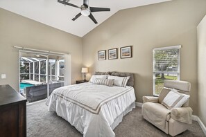 Relax in this serene bedroom with a large bed, armchair, and stunning pool view.