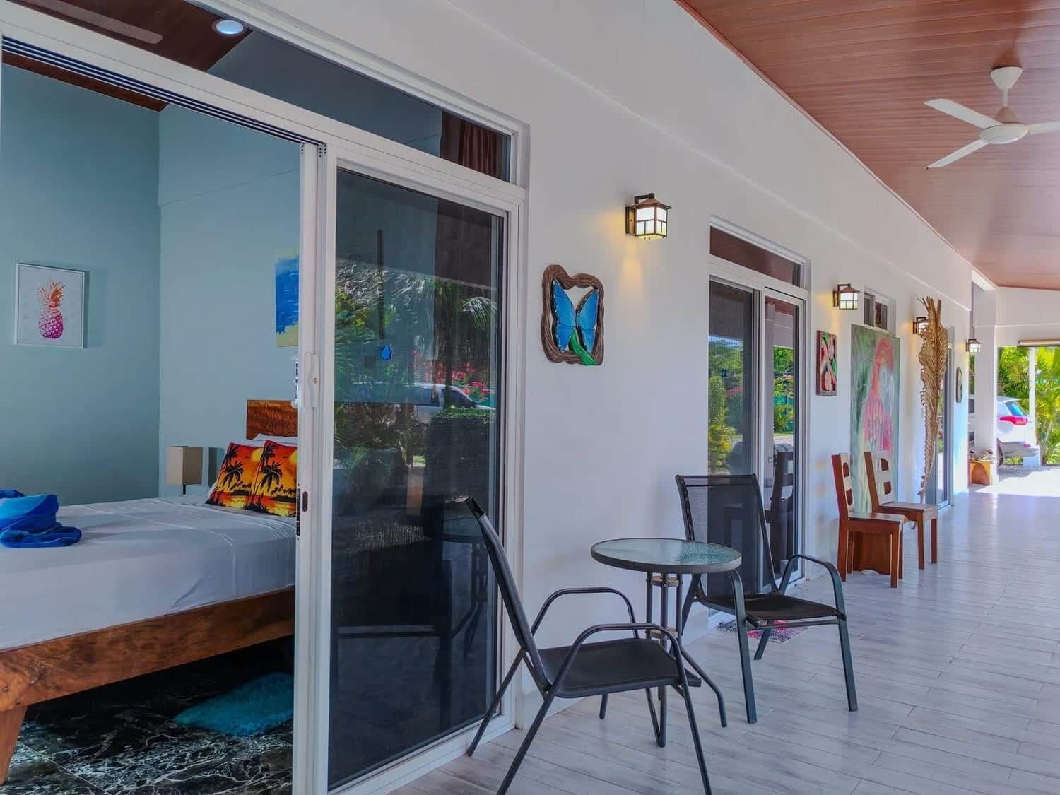 Une pièce comprenant un lit, une porte-fenêtre coulissante, une petite table avec des chaises et des œuvres d’art accrochées aux murs.
