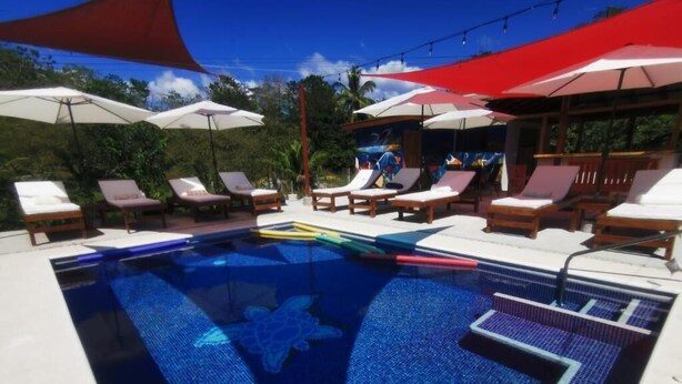 A swimming pool with lounge chairs and umbrellas. - Tuki Tuki Lodge, Tuki Tuki Lodge - Samara (Sámara)