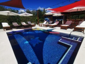 A swimming pool with lounge chairs and umbrellas. - Tuki Tuki Lodge, Tuki Tuki Lodge - Samara (Sámara)