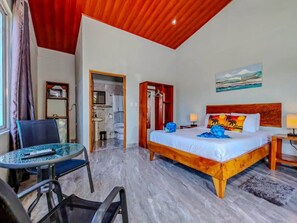 A hotel room with a bed, a chair, a table, a bathroom, and a painting on the wall. - Tuki Tuki Lodge, Tuki Tuki Lodge - Samara (Sámara)