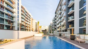 A modern residential building with a swimming pool, balconies, and a covered outdoor seating area. - Azizi Riviera Studio with Chic Furnishing (Dubai)