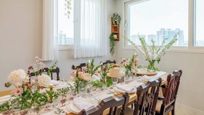Un'area pranzo con un tavolo apparecchiato per sei persone, decorata con composizioni floreali e una torta.