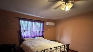 A bedroom with a bed, wooden flooring, a ceiling fan, and an air conditioning unit. - Charming 2-bedroom townhome in welcoming Heredia with WiFi, AC in walkable town (Heredia)