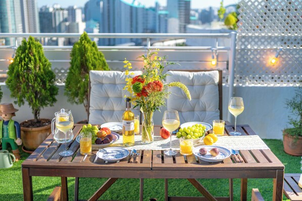 An outdoor dining table set with plates, glasses, and a vase of flowers.