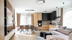 Ein modernes Wohnzimmer mit einer Couch, einem Couchtisch und einem Essbereich mit Stühlen.