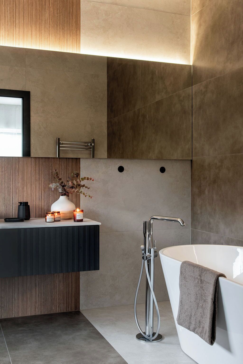A modern bathroom with a large bathtub, a vanity with a mirror, and a wall-mounted towel rack.