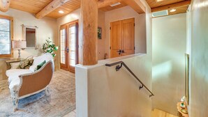 A room with a wooden ceiling, a white sofa with pillows, a wooden door, and a small table with a lamp. - Luxury Condo in the Heart of Santa Fe: Corazon 32 (Santa Fe)