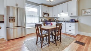 A modern kitchen with white cabinets, stainless steel appliances, and a dining area with a wooden table and chairs.