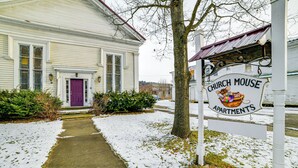 Un bâtiment blanc avec une porte violette et une enseigne indiquant « Church Mouse Apartments ».