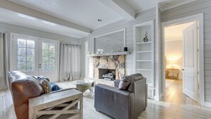A spacious living room with a stone fireplace, leather sofas, and a wooden coffee table. - Game Room, Trails! 30-Acre Lakefront Streetman Gem (Streetman)