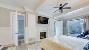 A bedroom with a bed, a television mounted above it, a ceiling fan, and a window with curtains. - Game Room, Trails! 30-Acre Lakefront Streetman Gem (Streetman)