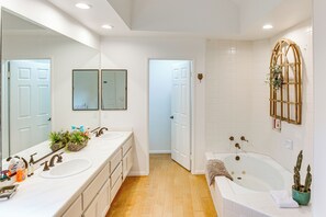 Features a double sink vanity, large mirror, and bathtub.