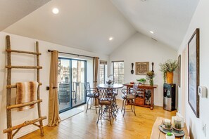 Enjoy a spacious room with a high ceiling, sliding glass door to an outdoor area, dining table, and refrigerator.
