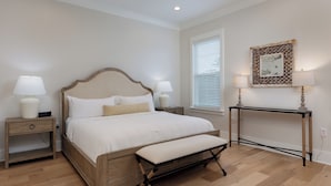 A bedroom with a bed, bedside tables, a bench, a console table, and a wall-mounted lamp. - 3BR/3BA perfect location in Ocean Springs-walk to downtown-Moondance on Magnolia (Ocean Springs)