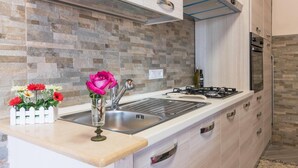 Una cocina moderna con protector contra salpicaduras de piedra, un lavamanos de acero inoxidable y una estufa a gas.