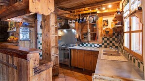 A rustic kitchen with wooden cabinets, a stove, and hanging pots.