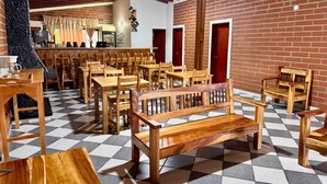 Un ristorante con tavoli e sedie di legno, un pavimento a scacchi e un muro in mattoni.