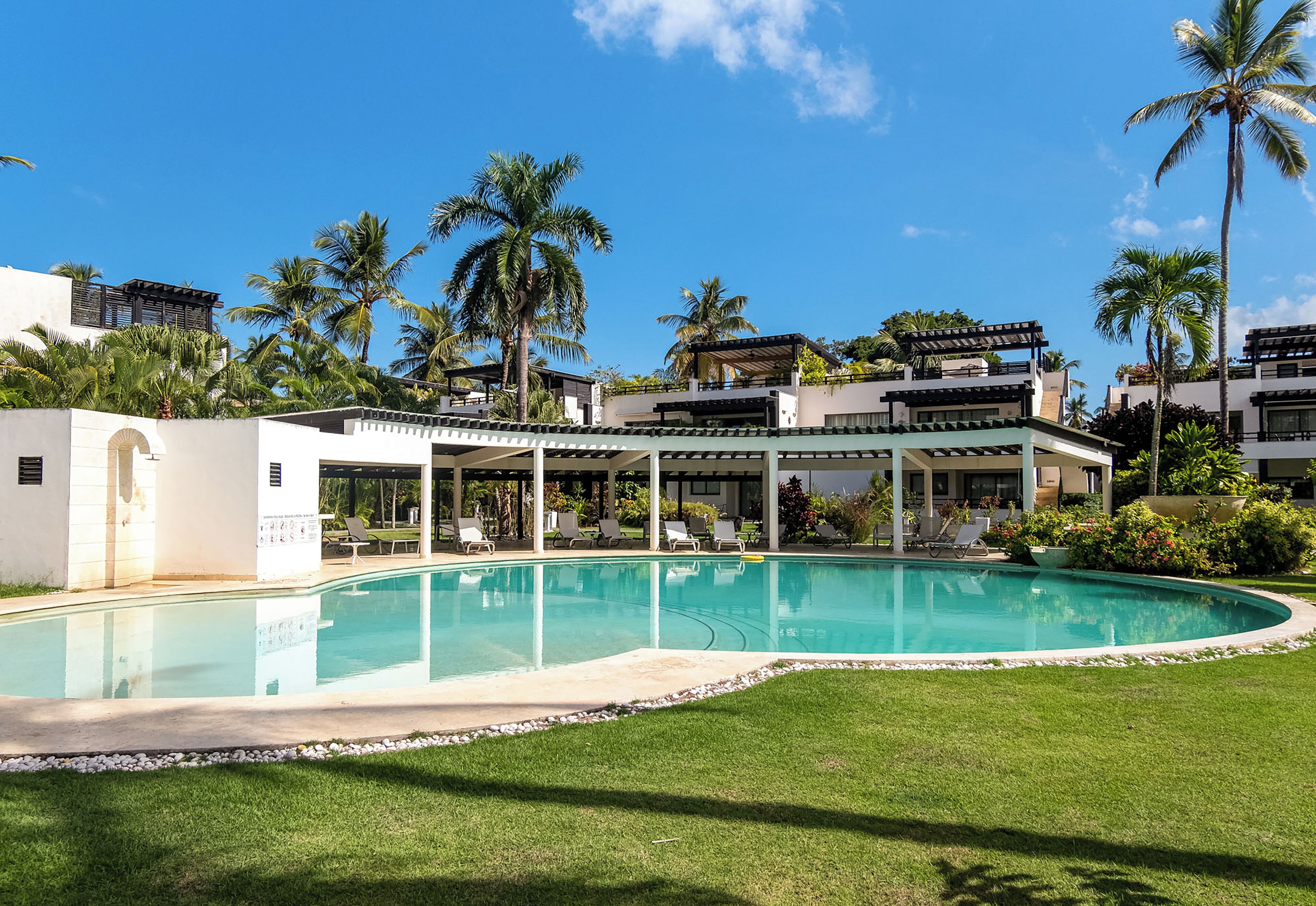 A swimming pool surrounded by palm trees and modern buildings.