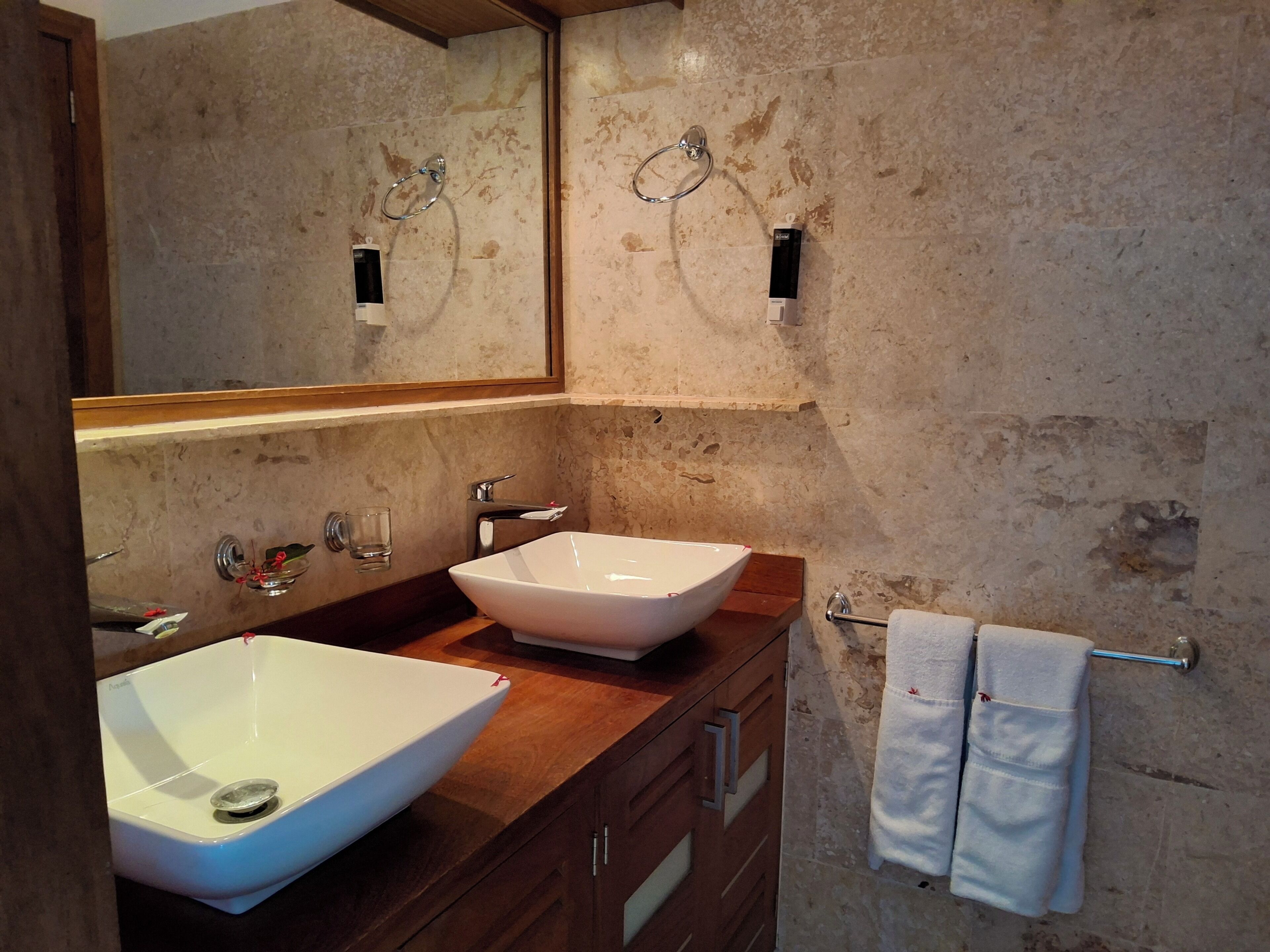 Een badkamer met twee wasbakken, een spiegel, een handdoekhouder en een houten opbergmeubel.