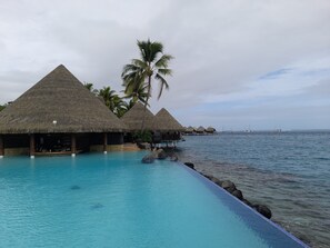 An infinity pool with overwater bungalows and a view of the ocean. - Manureva Lodge (Faa'a)