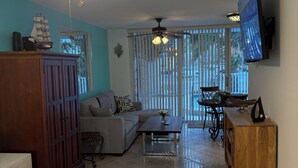 A bedroom with a bed, a wooden wardrobe, a ceiling fan, and a TV mounted on the wall. - Charming and Spacious Studio in Delightful Clearwater Beach (Clearwater Beach)