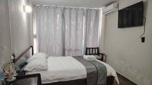 A bedroom with a bed, a bedside table, a chair, and an air conditioning unit on the wall. - Hotel la fortuna (Tuxpan)