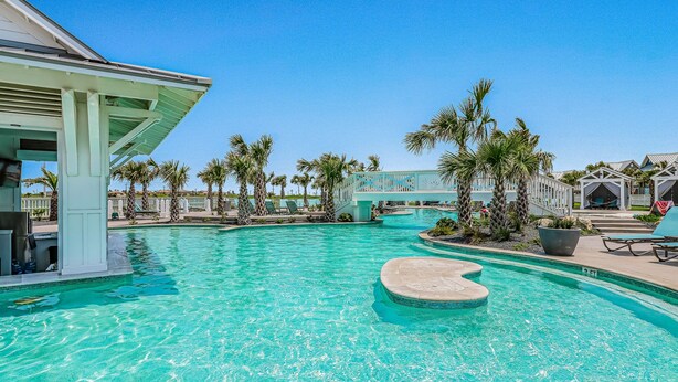 A swimming pool with a heart-shaped island, surrounded by palm trees and lounge chairs.