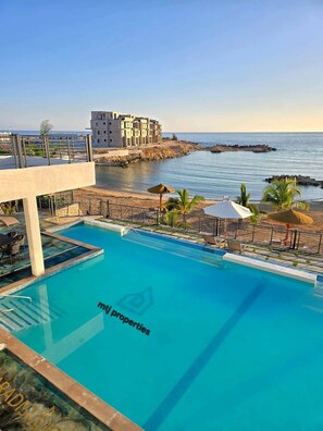 A swimming pool with a view of the sea and a building in the background. - The Onyx Beach Villa by MTJ Properties (Plantation Village)