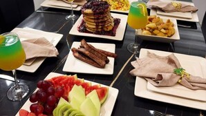 A dining table set with various dishes, including pancakes, fruit, and a small plant.