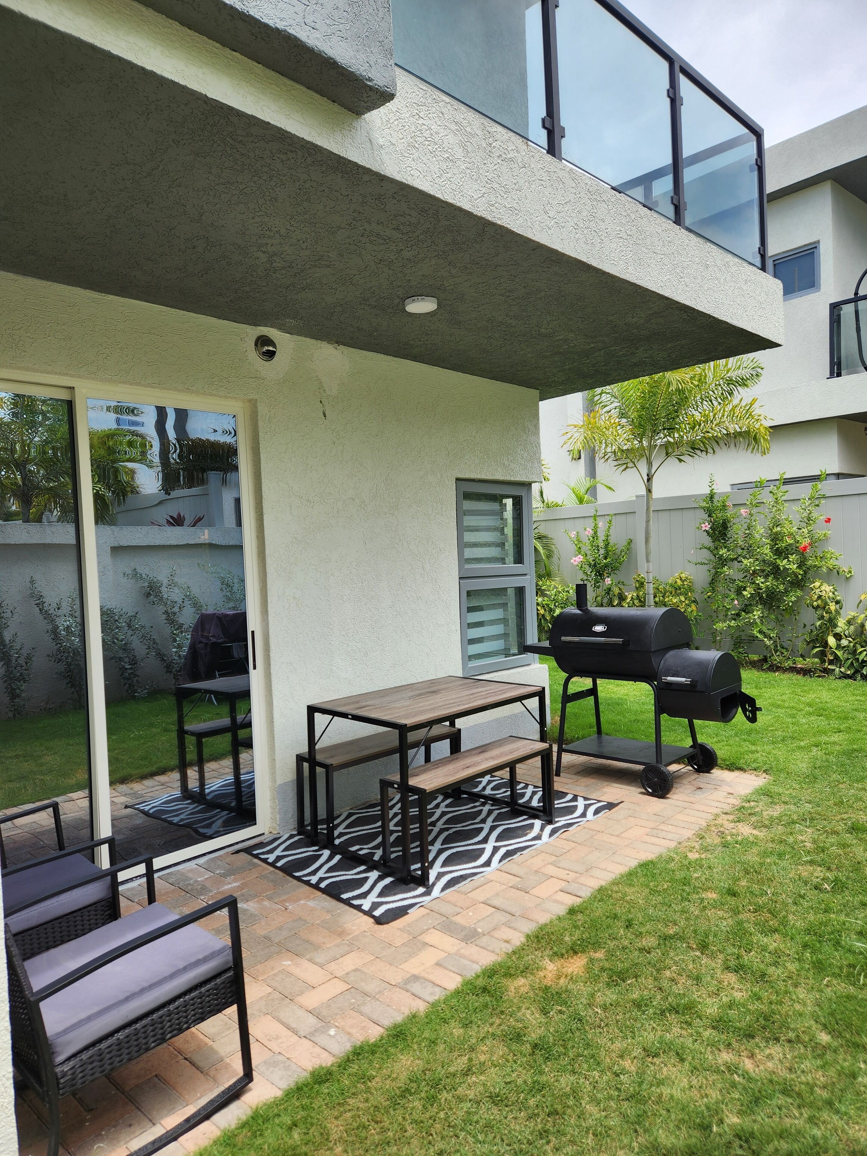 Eine Terrasse mit Grill, Tisch und Sitzgelegenheiten im Freien.