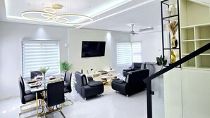 Una sala de estar moderna con comedor, una escalera y un televisor montado en la pared.