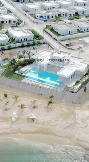 An aerial view of a residential area with white buildings, a swimming pool, and a beach. - The Onyx Beach Villa by MTJ Properties (Plantation Village)