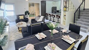 Un comedor moderno con una mesa negra dispuesta para seis personas, rodeada de sillas tapizadas en negro.